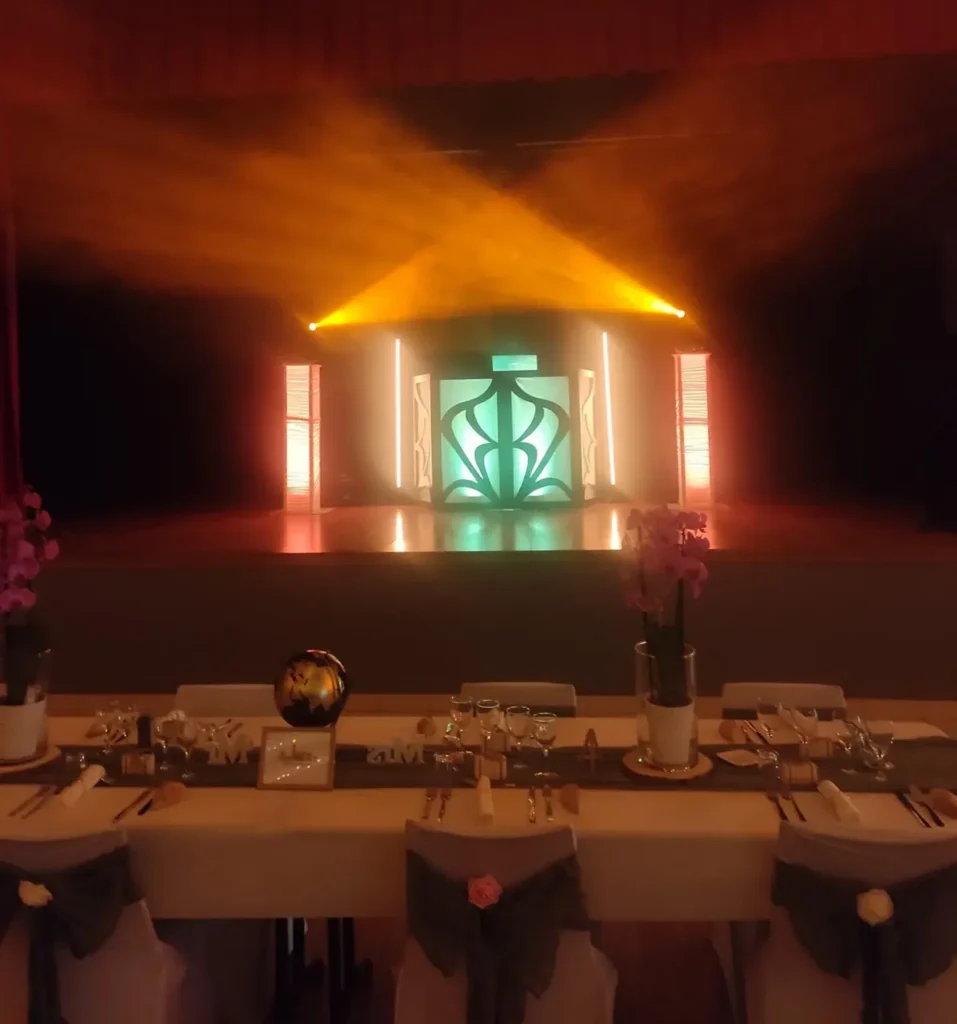 Décoration de salle de réception avec scène éclairée et table d’honneur pour mariage